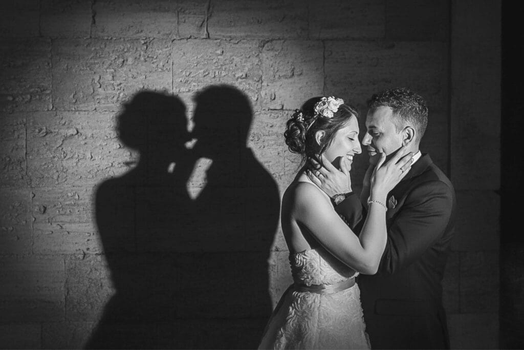 Fotografia artistica in bianco e nero con le ombre degli sposi su un muro antico